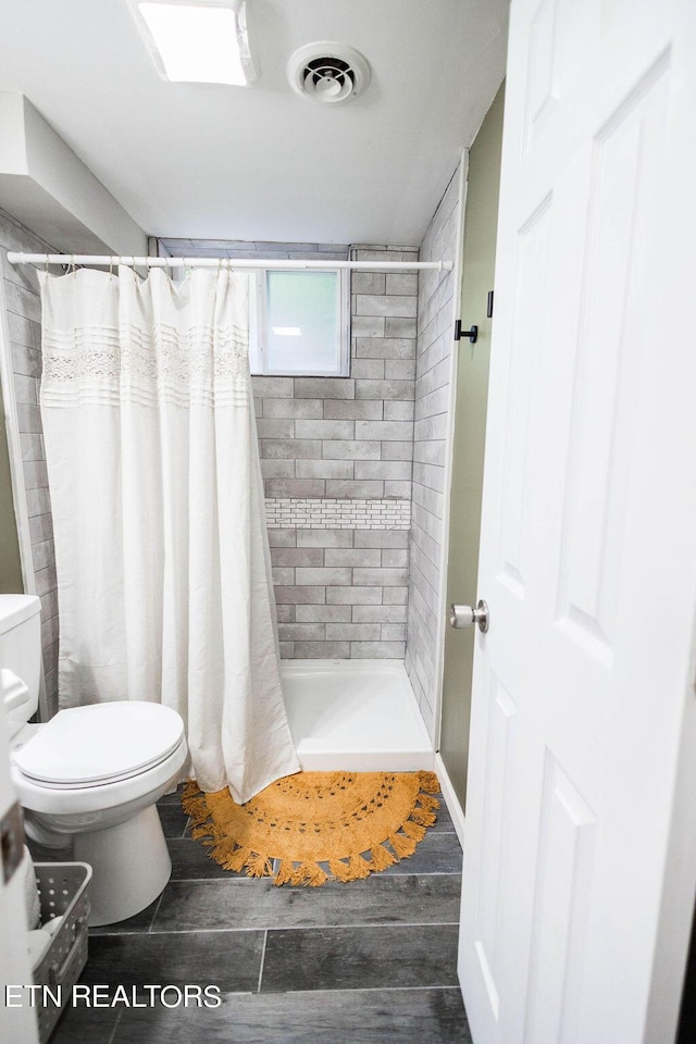 full bath with toilet, wood finished floors, a shower stall, and visible vents