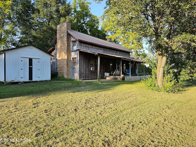 rear view of house with a shed and a lawn