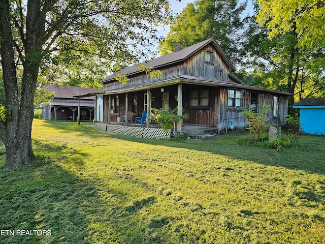 rear view of property with an outdoor structure, a porch, and a yard