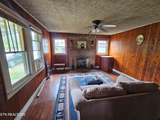 living room with wood walls, a wealth of natural light, dark wood-type flooring, and a fireplace