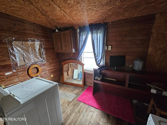 interior space with wood walls, light hardwood / wood-style flooring, and washer / clothes dryer