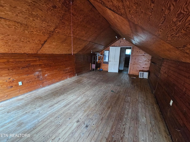 bonus room with hardwood / wood-style flooring, wooden walls, and vaulted ceiling