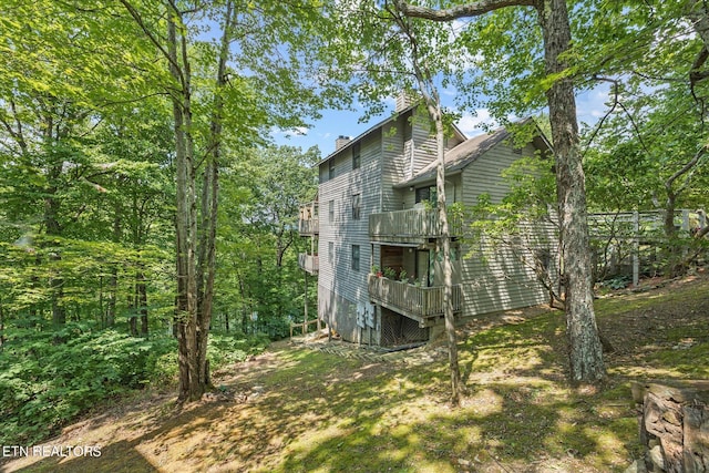 view of home's exterior with a chimney and a balcony