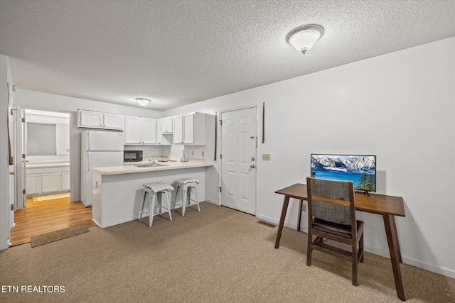 kitchen featuring light hardwood / wood-style floors, a kitchen breakfast bar, white cabinets, kitchen peninsula, and white refrigerator