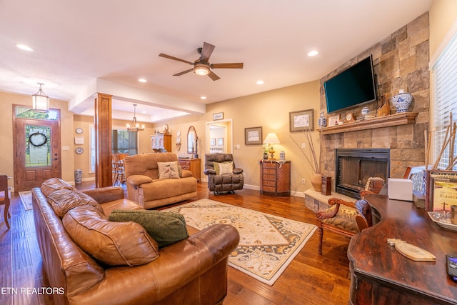 living room with wood-type flooring, ceiling fan with notable chandelier, and a fireplace