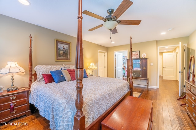 bedroom with dark hardwood / wood-style flooring, ceiling fan, a walk in closet, and a closet