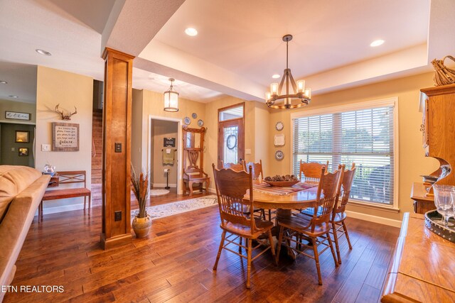 dining room featuring ornate columns, a chandelier, and dark wood-type flooring