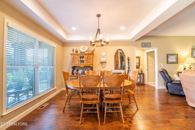 dining area featuring a notable chandelier, a raised ceiling, and dark hardwood / wood-style floors