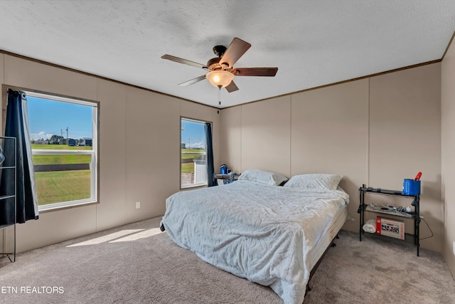 bedroom with light colored carpet, a textured ceiling, crown molding, and ceiling fan