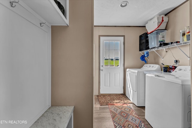 laundry room with a textured ceiling, light hardwood / wood-style floors, ornamental molding, and washing machine and clothes dryer