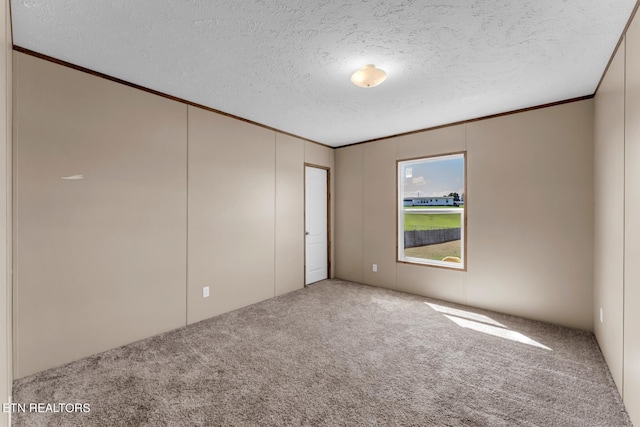 unfurnished room with a textured ceiling, carpet, and ornamental molding