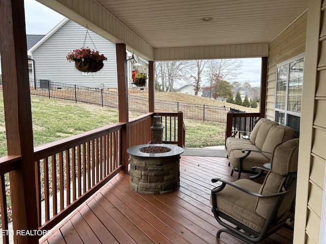 deck featuring a fenced backyard, a lawn, and a fire pit