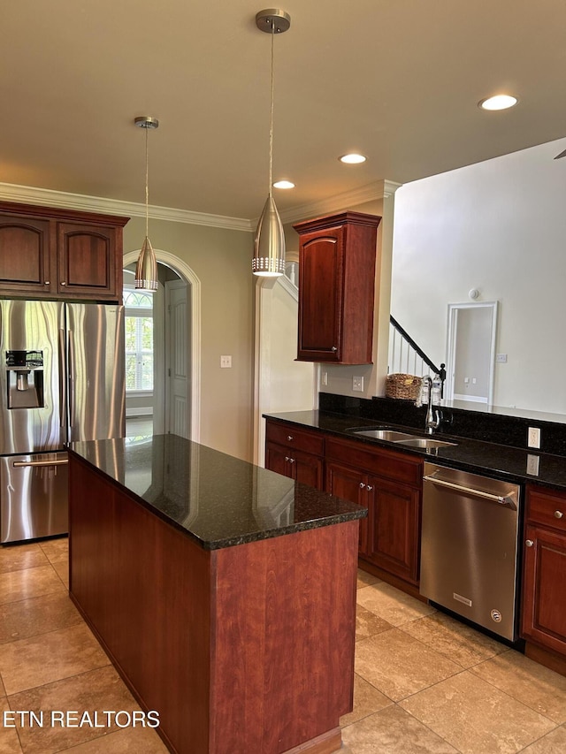 kitchen featuring a center island, a sink, dark stone countertops, ornamental molding, and stainless steel appliances