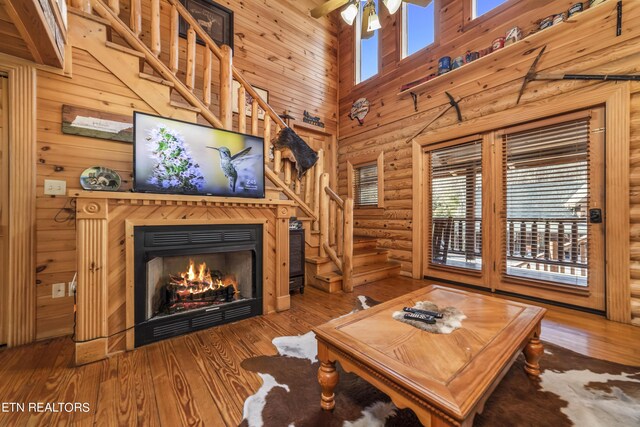 living room with a towering ceiling, ceiling fan, and wood-type flooring