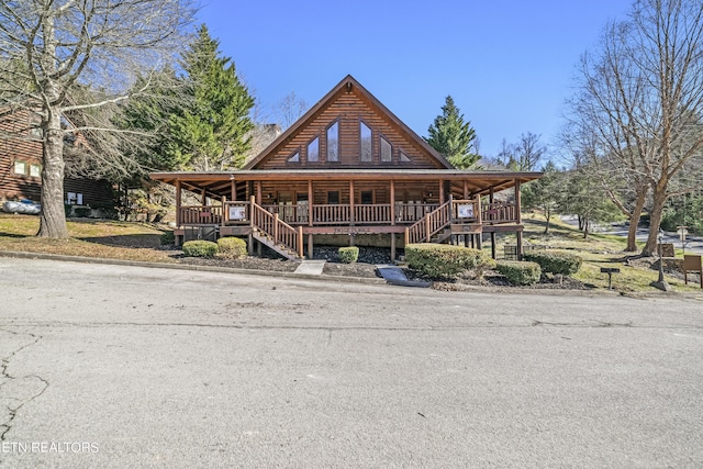 view of front facade featuring covered porch, log exterior, and stairway