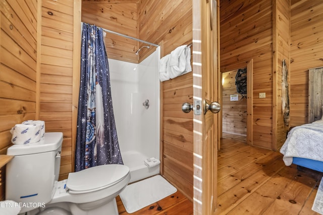 full bath featuring toilet, a stall shower, wood-type flooring, and wooden walls