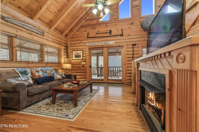 living area with high vaulted ceiling, wood ceiling, light wood-type flooring, beamed ceiling, and a glass covered fireplace