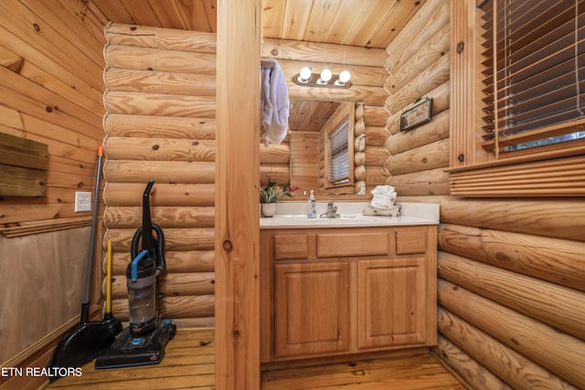 bathroom with vanity, wood finished floors, and log walls