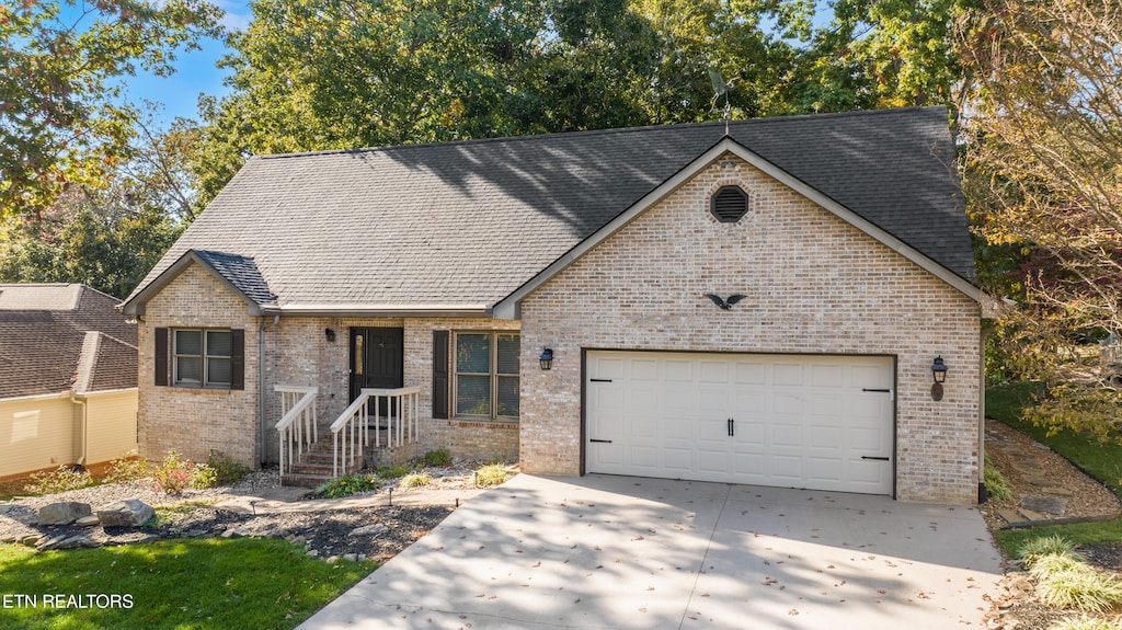 view of front of home featuring a garage, driveway, roof with shingles, and brick siding