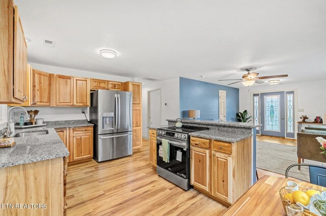 kitchen with stainless steel appliances, sink, light stone counters, light wood-type flooring, and ceiling fan