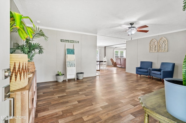 living room with ceiling fan, crown molding, wood-type flooring, and a textured ceiling