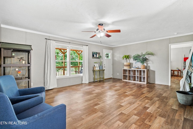 living room featuring ornamental molding, a ceiling fan, a textured ceiling, and wood finished floors