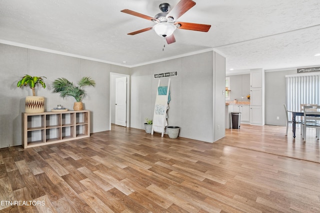 empty room with ornamental molding, a textured ceiling, and light wood finished floors