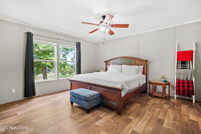 bedroom with hardwood / wood-style flooring, a textured ceiling, and ceiling fan