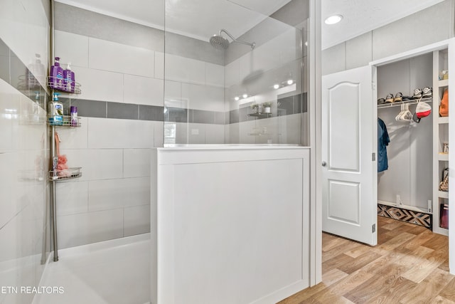 bathroom with tiled shower and wood-type flooring