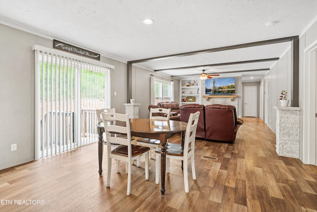 dining room featuring ornamental molding, built in features, light wood-type flooring, a textured ceiling, and ceiling fan