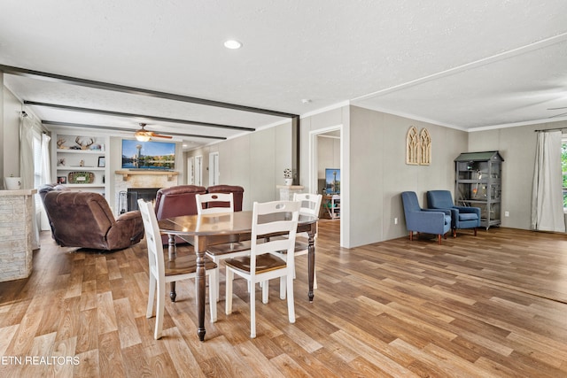 dining area with light hardwood / wood-style flooring, ornamental molding, built in features, a textured ceiling, and ceiling fan