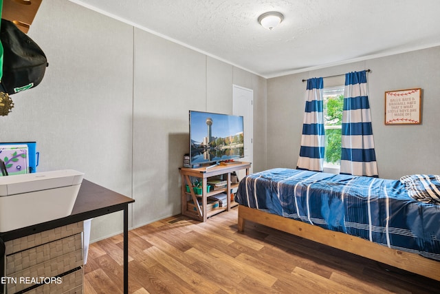 bedroom with a textured ceiling and light wood-type flooring