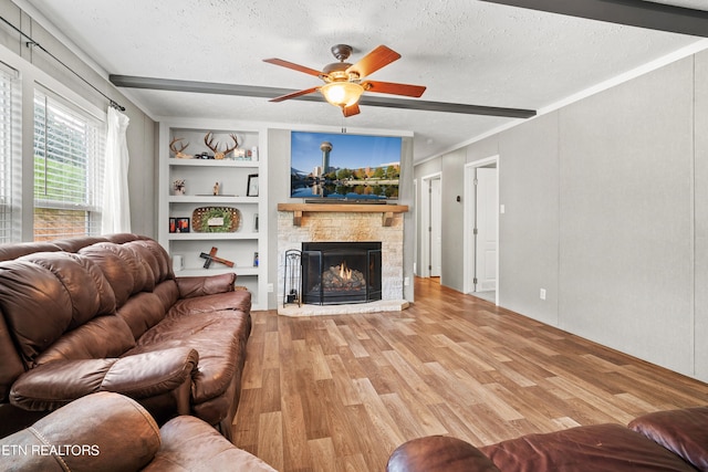 living room with built in features, light wood-type flooring, a textured ceiling, a fireplace, and ceiling fan