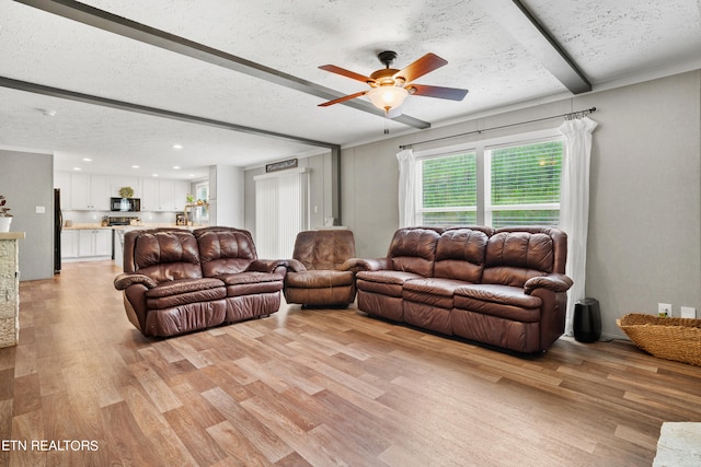 living room with ceiling fan, light hardwood / wood-style flooring, and a textured ceiling