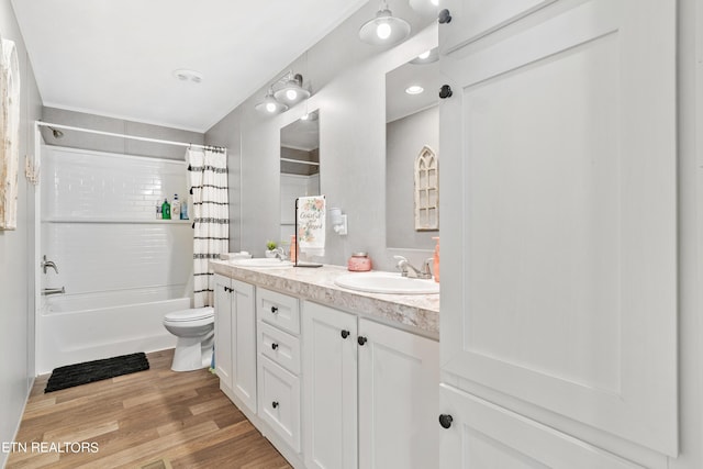 full bathroom with double vanity, shower / tub combo with curtain, a sink, and wood finished floors