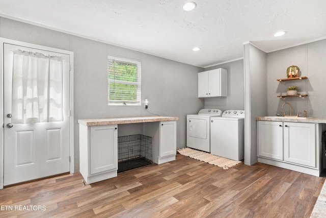 washroom featuring light wood-type flooring, cabinets, independent washer and dryer, sink, and a textured ceiling