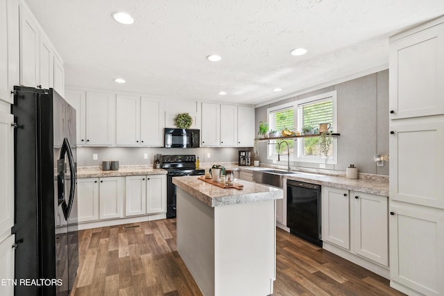 kitchen featuring black appliances, a kitchen island, and white cabinets