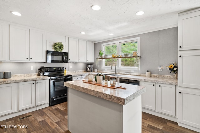 kitchen with dark hardwood / wood-style flooring, white cabinets, black appliances, and a center island