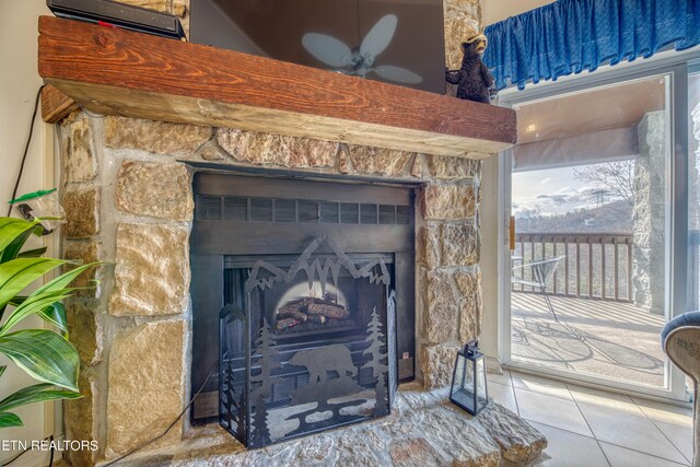 room details featuring ceiling fan, tile patterned flooring, and a stone fireplace