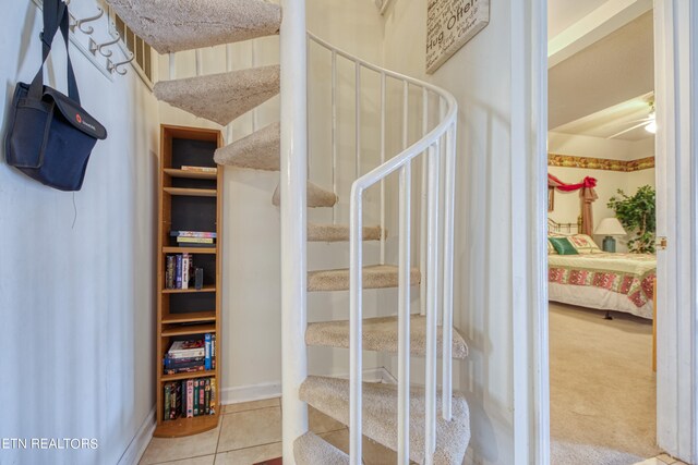 staircase featuring ceiling fan and tile patterned flooring