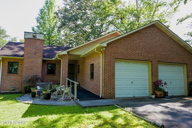 exterior space with driveway, a chimney, a garage, and brick siding