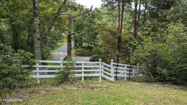 view of gate featuring a fenced front yard and a forest view