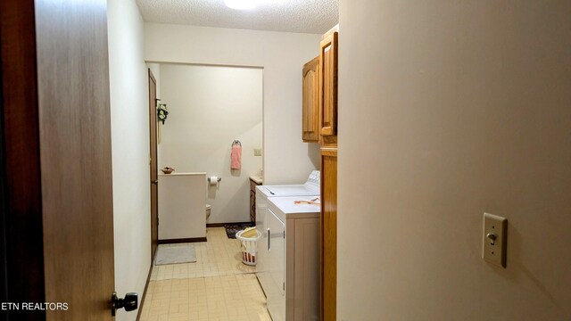 washroom with a textured ceiling, light tile patterned floors, cabinets, and washer and dryer