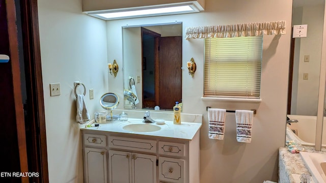 bathroom with a tub to relax in, vanity, and a skylight