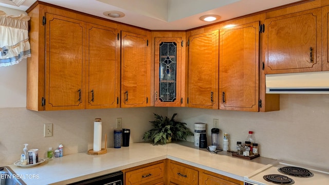 kitchen featuring brown cabinets, range with electric stovetop, light countertops, and range hood
