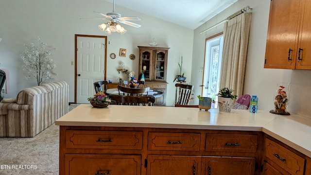 kitchen with open floor plan, light countertops, vaulted ceiling, a peninsula, and brown cabinetry