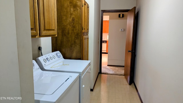 laundry area with baseboards, cabinet space, washer and dryer, and light floors
