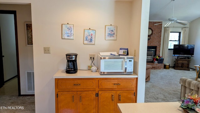 kitchen with light countertops, visible vents, carpet, a brick fireplace, and white microwave