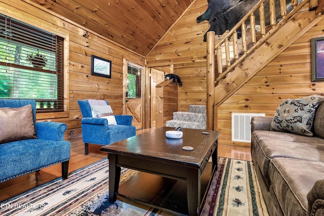 living room with a wealth of natural light, vaulted ceiling, wood-type flooring, and wooden walls