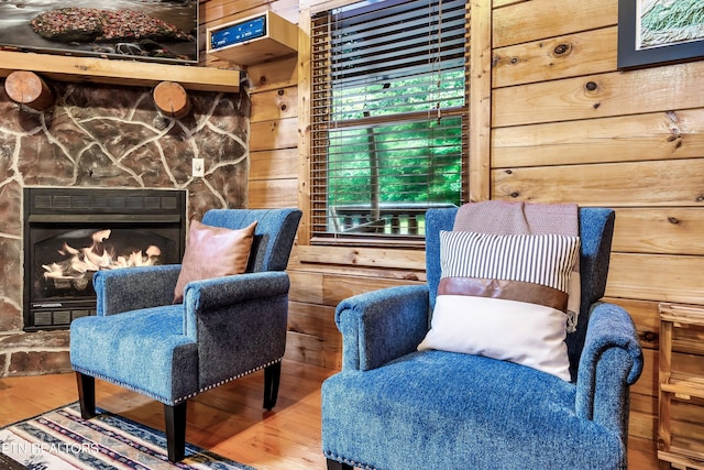 sitting room featuring a fireplace, wooden walls, and wood-type flooring